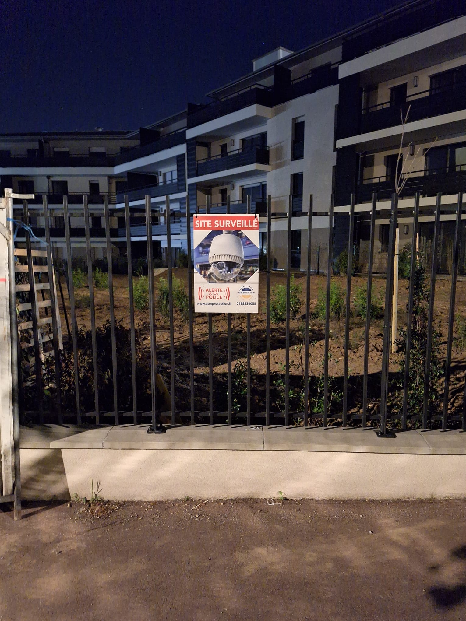 Panneau ASM Protection visible de nuit devant une copropriété en travaux